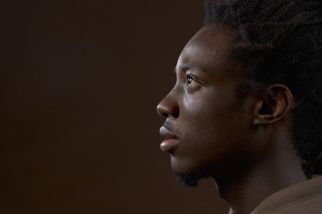 The Art of Drawing Readers In: Your attractive post title goes here Studio portrait profile of a young black man against a brown background.
